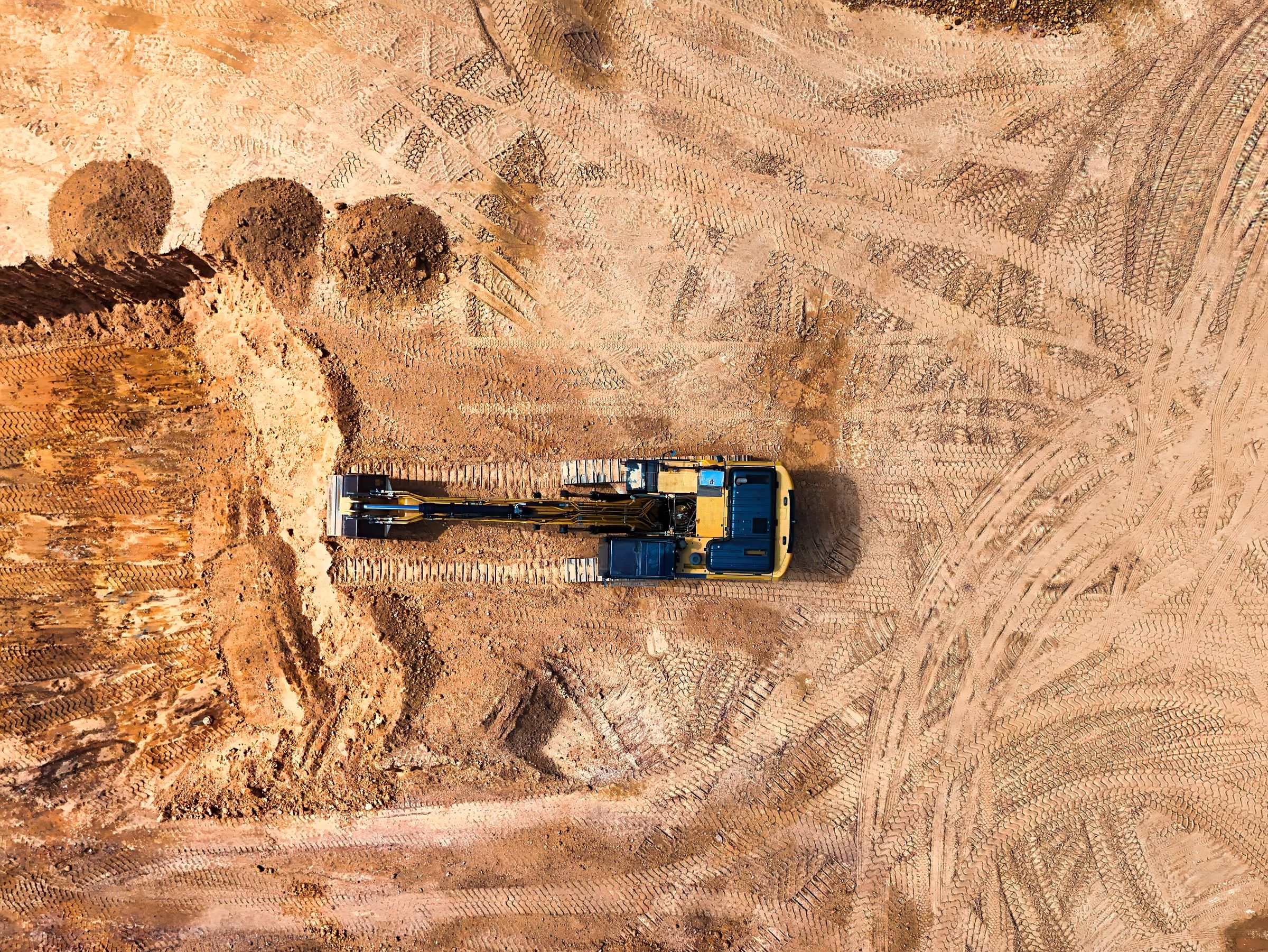 Aerial view of an excavator working a graded earthworks site