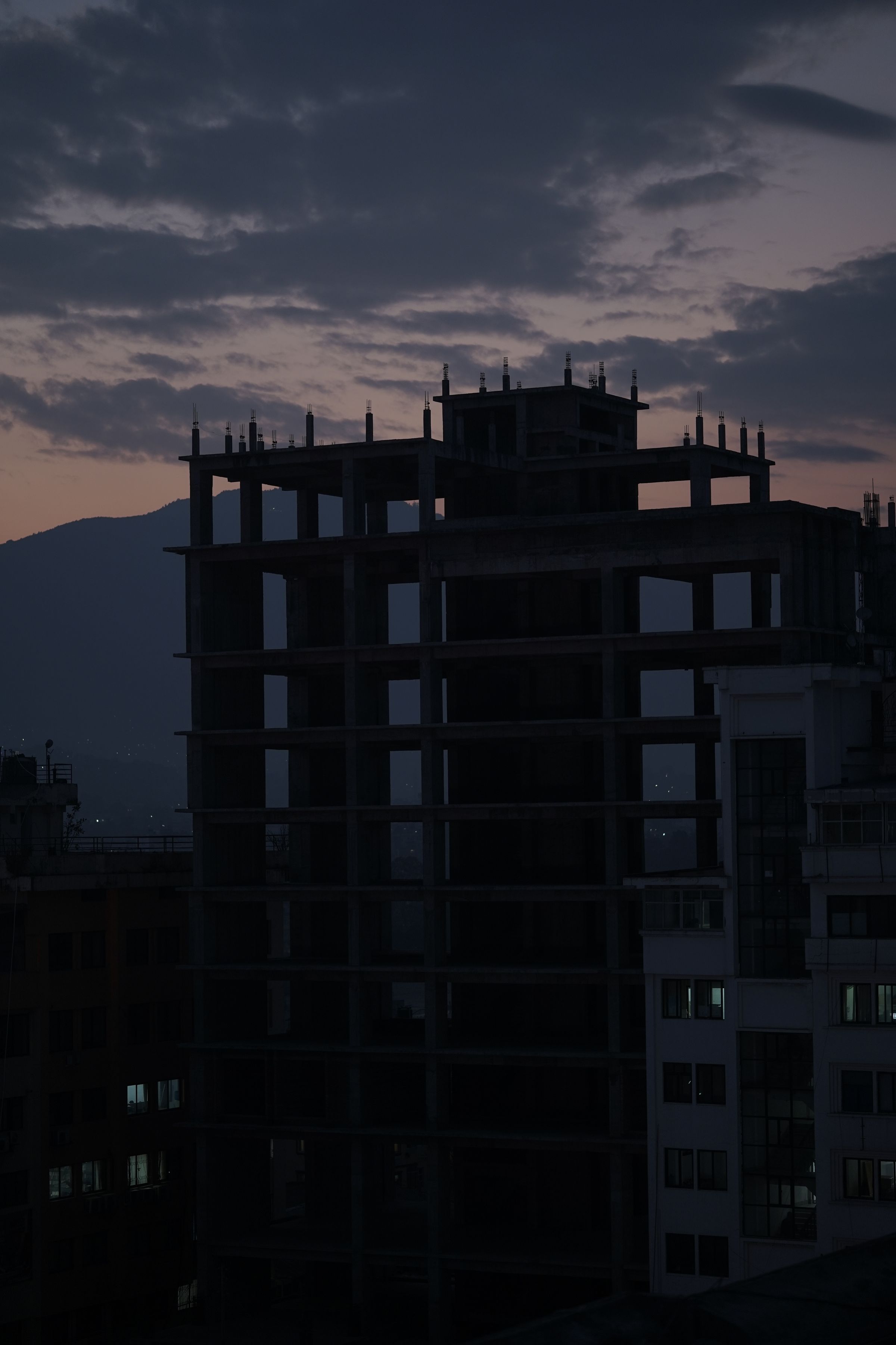 Concrete building frame silhouetted against dusk cloud